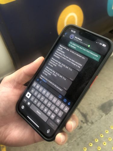 这张图片显示了新的whatsapp服务我们ed on a phone next to a Northern train