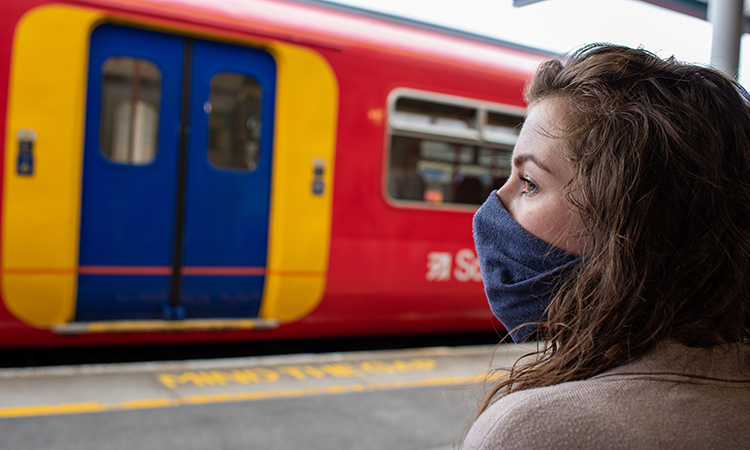 一名女子在火车站戴口罩，以保护自己和他人不感染和传播COVID-19