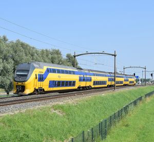 典型的荷兰黄蓝色城际VIRM动车组列车在绿色自然环境，阳光明媚的天气在蓝天下