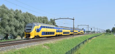 典型的荷兰黄蓝色城际VIRM动车组列车在绿色自然环境，阳光明媚的天气在蓝天下