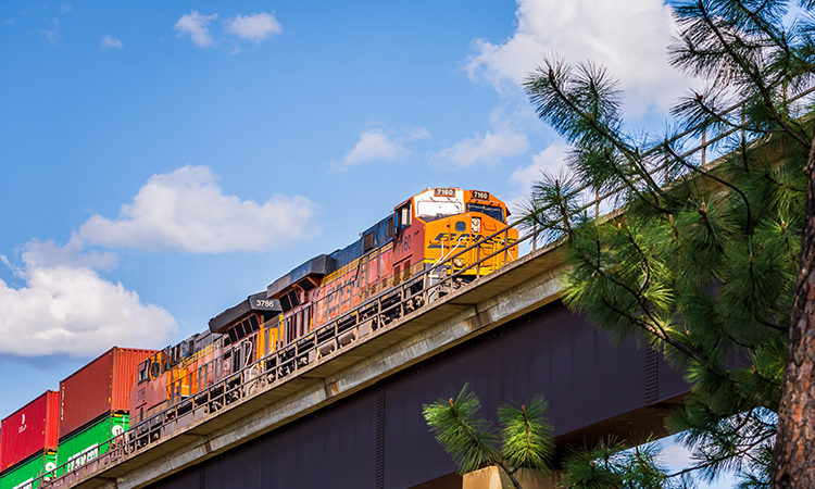 从下面看到的两个BNSF火车头拉着汽车越过一个极高的高架桥的低角度视图。