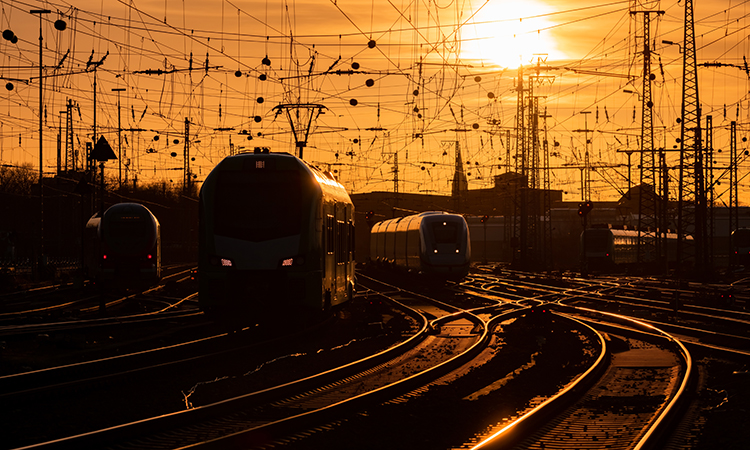 火车在温暖的夜色中抵达多特蒙德车站，弯曲的主线铁轨在阳光下闪闪发光。