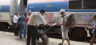 铁路售票员和车站工作人员协助乘客登上美国铁路公司的火车。